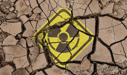 Image of Yellow radioactive sign on cracked dry earth, top view. Radiological pollution