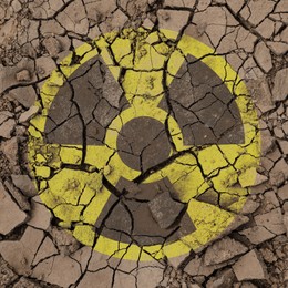 Image of Yellow radioactive sign on cracked dry earth, top view. Radiological pollution
