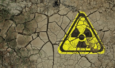 Image of Yellow radioactive sign on cracked dry earth, top view. Radiological pollution