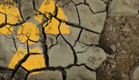 Image of Orange radioactive sign on cracked dry earth, top view. Radiological pollution