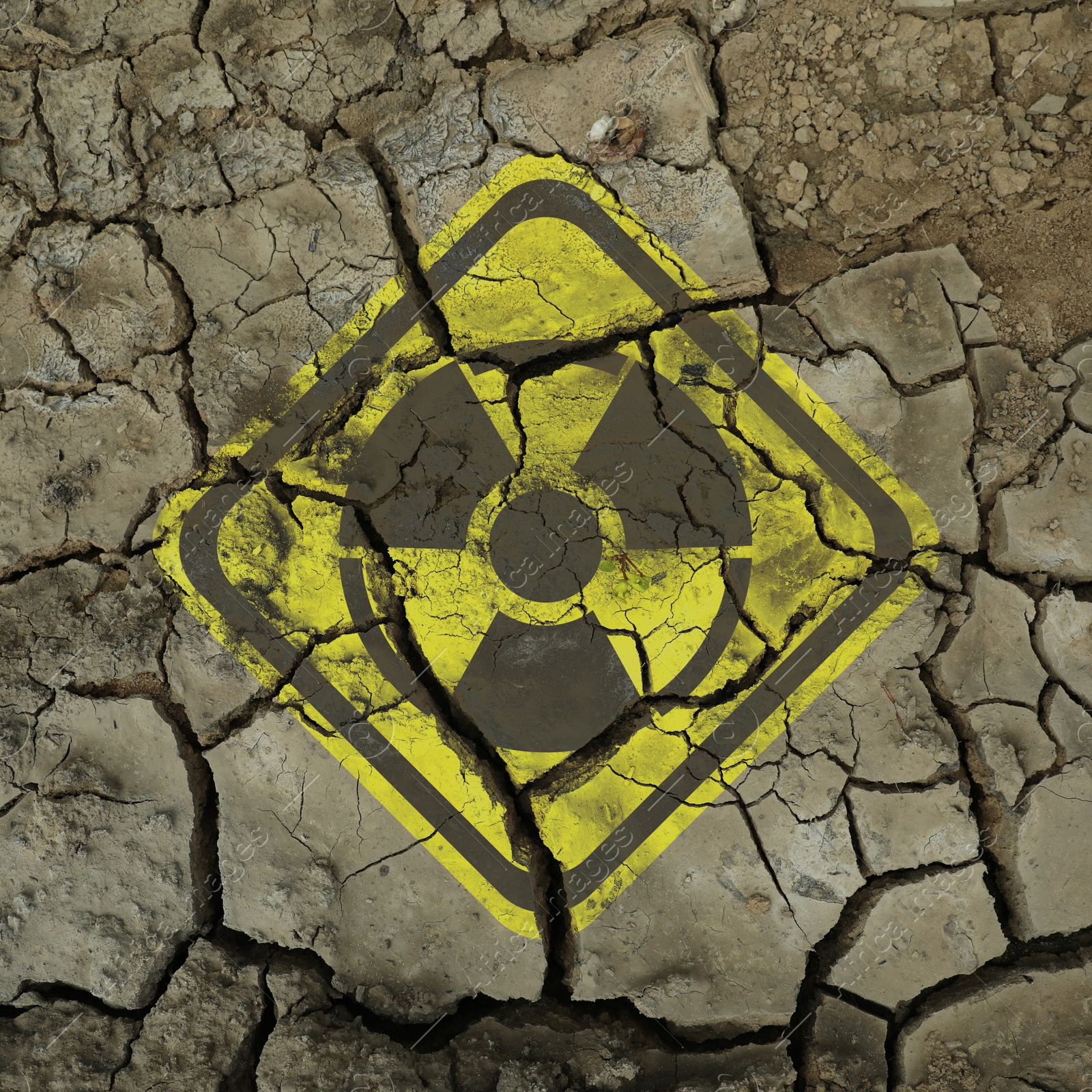Image of Yellow radioactive sign on cracked dry earth, closeup. Radiological pollution
