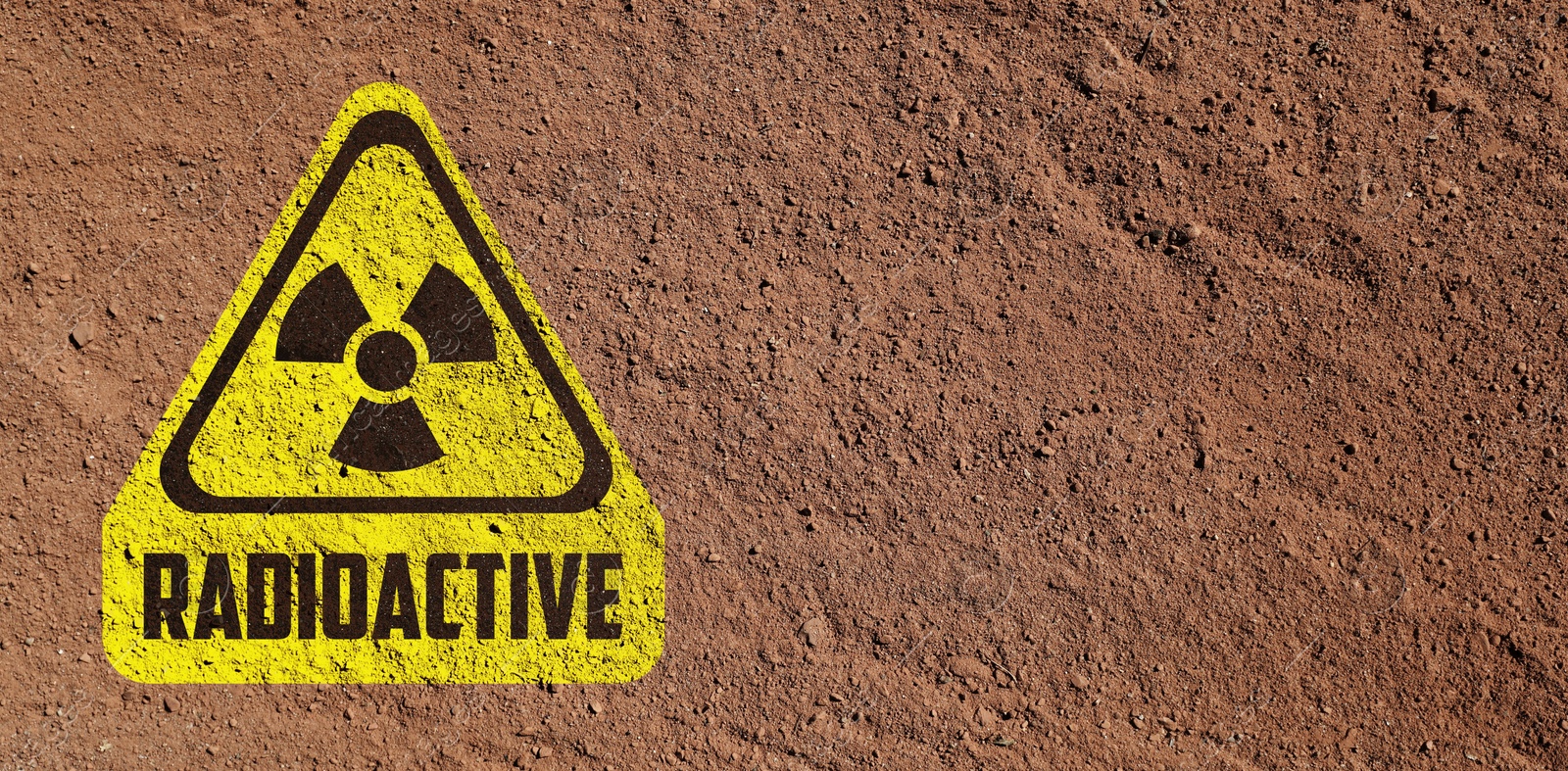 Image of Yellow radioactive sign on brown ground, top view. Radiological pollution