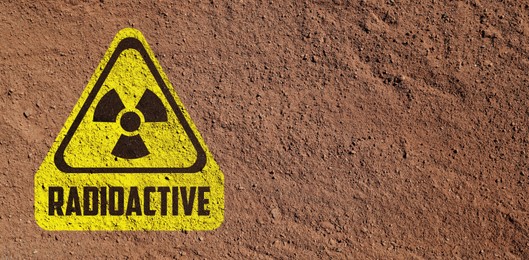 Image of Yellow radioactive sign on brown ground, top view. Radiological pollution