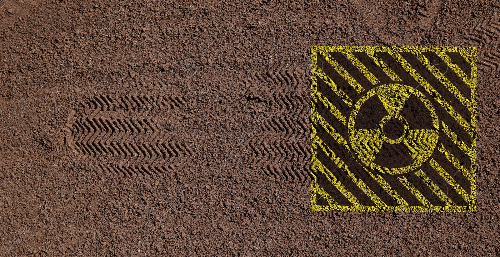 Image of Yellow radioactive sign on brown ground with shoes tracks, top view. Radiological pollution