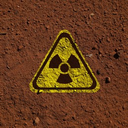 Image of Yellow radioactive sign on brown ground, top view. Radiological pollution