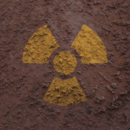 Image of Orange radioactive sign on brown ground, top view. Radiological pollution