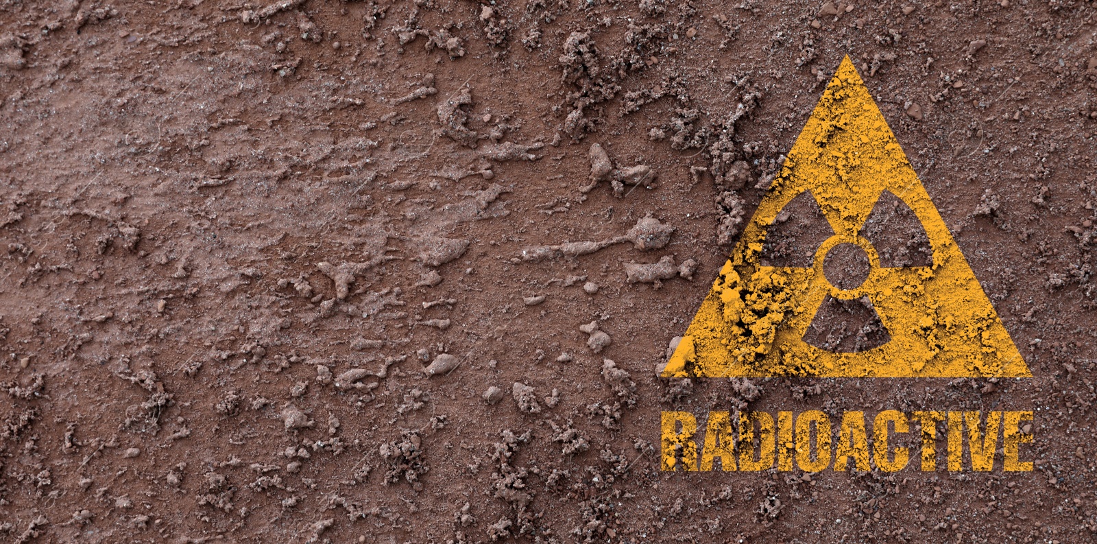 Image of Orange radioactive sign on brown ground, top view. Radiological pollution