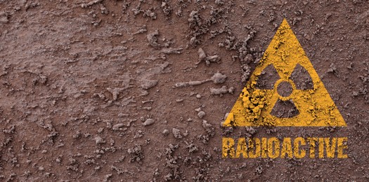 Image of Orange radioactive sign on brown ground, top view. Radiological pollution