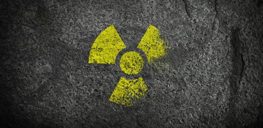Image of Yellow radioactive sign on dark stone background, banner design. Radiological pollution