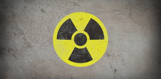 Image of Yellow radioactive sign on grey stone background, banner design. Radiological pollution