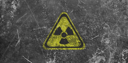 Image of Yellow radioactive sign on grey textured background, banner design. Radiological pollution