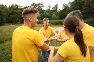 Photo of Team building. Group of happy people joining hands outdoors