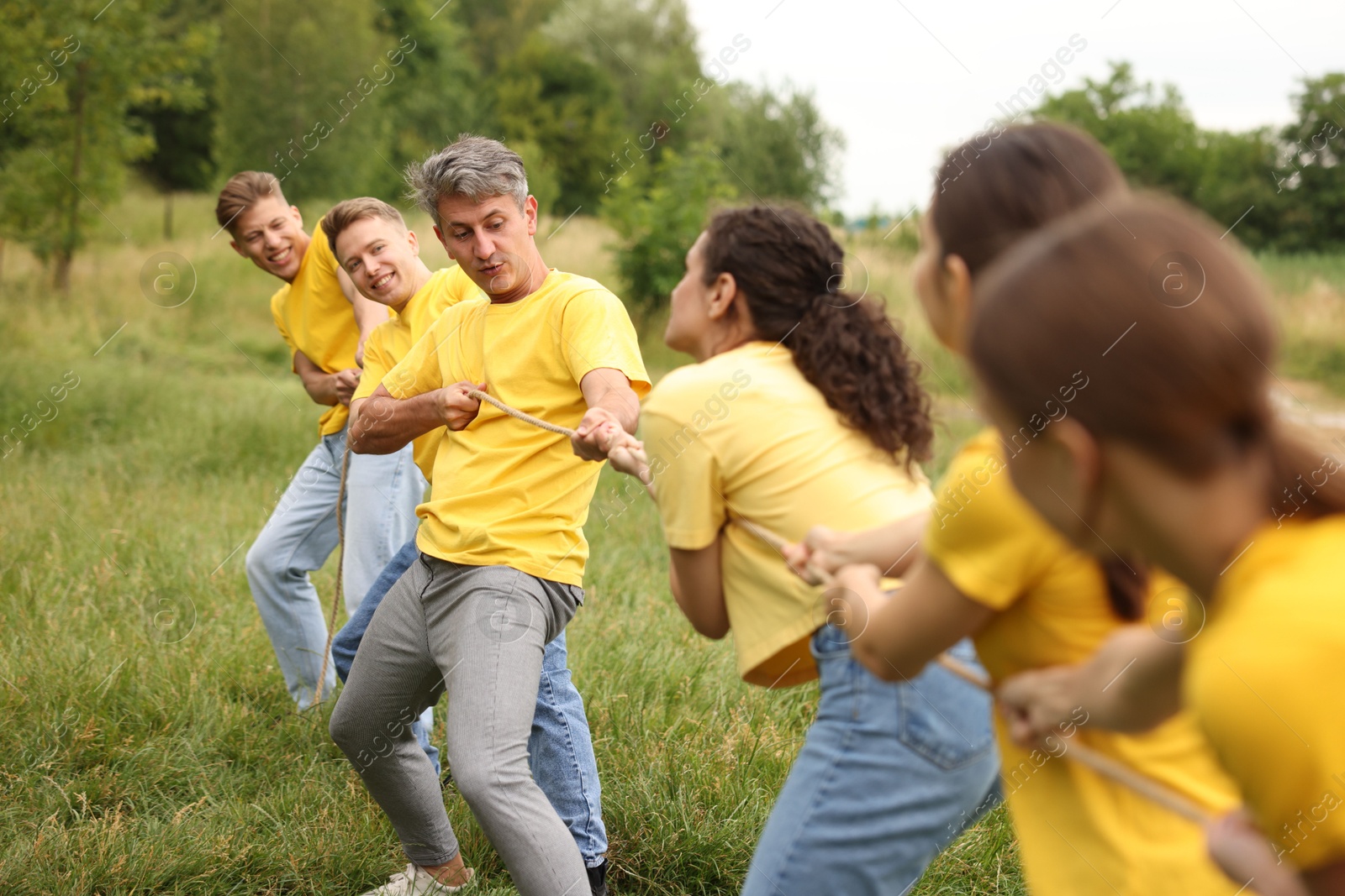 Team building. Group of happy people playing tug of war with rope outdoors Photo of Team building. Group of happy people playing tug of war with rope outdoors