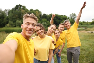 Photo of Team building. Group of happy people taking selfie outdoors