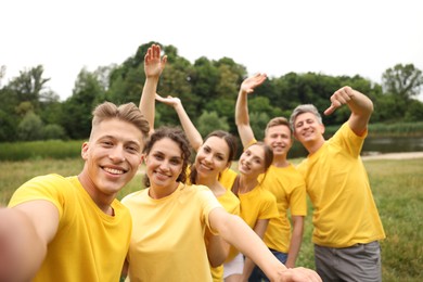 Photo of Team building. Group of happy people taking selfie outdoors