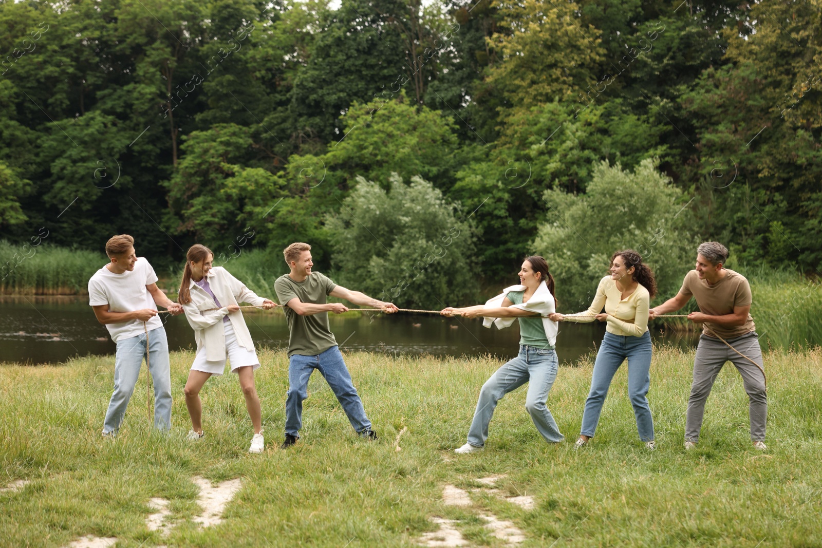 Team building. Group of happy people playing tug of war with rope outdoors Photo of Team building. Group of happy people playing tug of war with rope outdoors