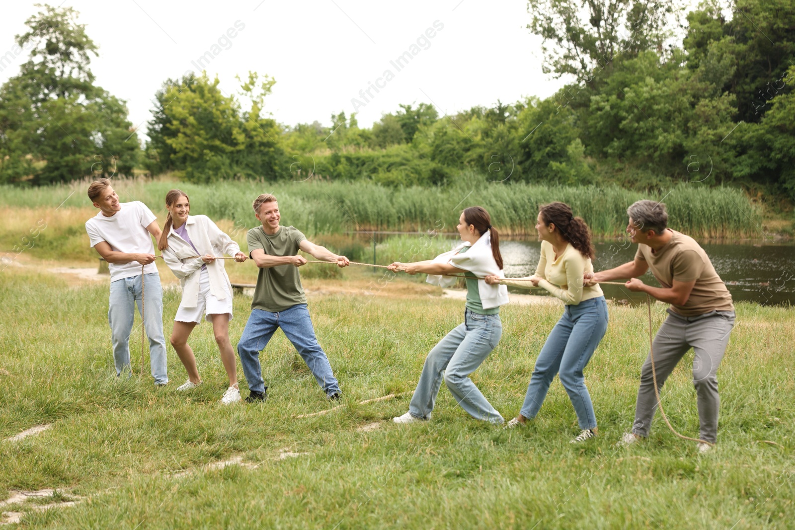 Team building. Group of happy people playing tug of war with rope outdoors Photo of Team building. Group of happy people playing tug of war with rope outdoors