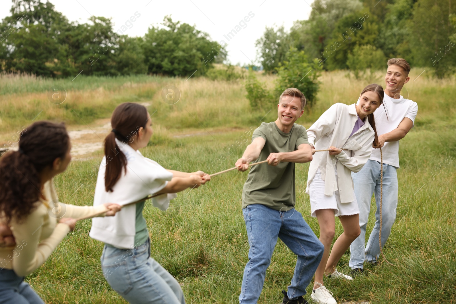 Team building. Group of happy people playing tug of war with rope outdoors Photo of Team building. Group of happy people playing tug of war with rope outdoors