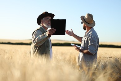 Photo of Farmers in field with ripe wheat outdoors