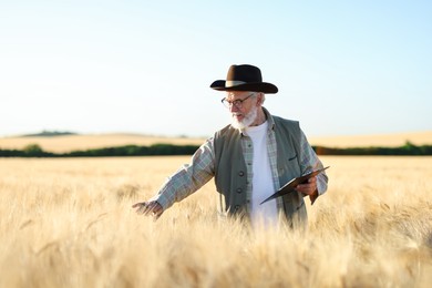 Photo of Senior farmer with clipboard in field of ripe wheat outdoors