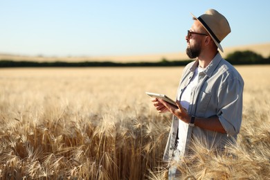 Photo of Farmer with tablet in field of ripe wheat outdoors, space for text