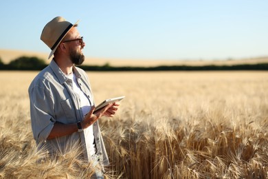 Photo of Farmer with tablet in field of ripe wheat outdoors, space for text