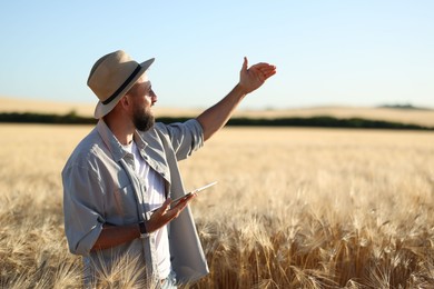 Photo of Farmer with tablet in field of ripe wheat outdoors, space for text
