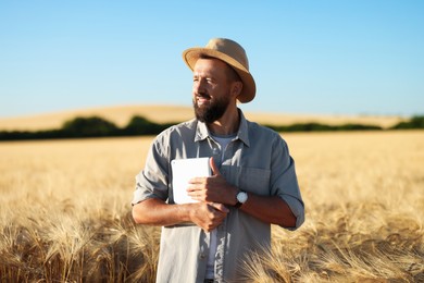 Photo of Farmer with tablet in field of ripe wheat outdoors