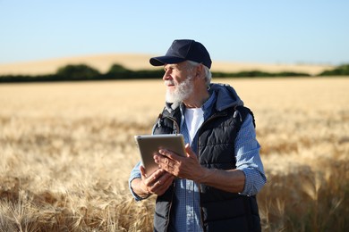 Photo of Senior farmer with tablet in field of ripe wheat outdoors
