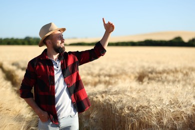 Photo of Farmer in field with ripe wheat outdoors, space for text