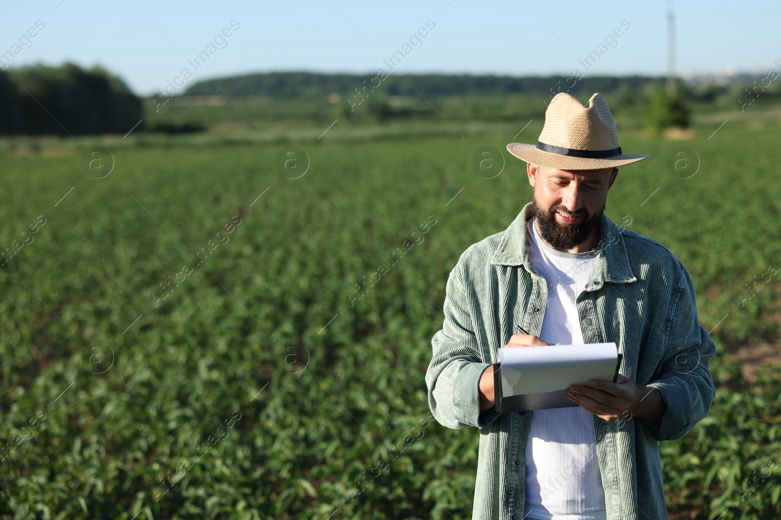 Farmer with clipboard in field of unripe soy outdoors, space for text Photo of Farmer with clipboard in field of unripe soy outdoors, space for text