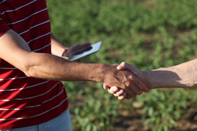 Photo of Farmers shaking hands in field outdoors, closeup