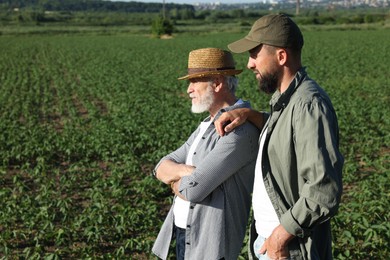 Photo of Farmers in field of unripe soy outdoors, space for text