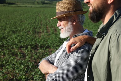 Photo of Farmers in field of unripe soy outdoors, space for text