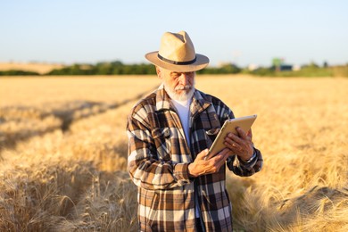 Photo of Senior farmer with tablet in field of ripe wheat outdoors