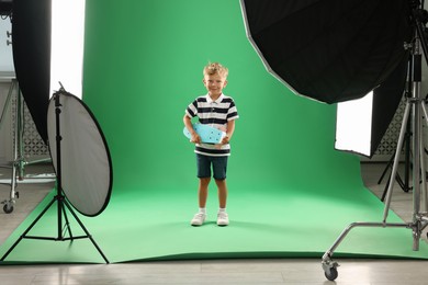 Photo of Little boy with penny board on green background in photo studio with professional equipment