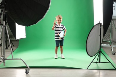 Photo of Little boy with penny board on green background in photo studio with professional equipment