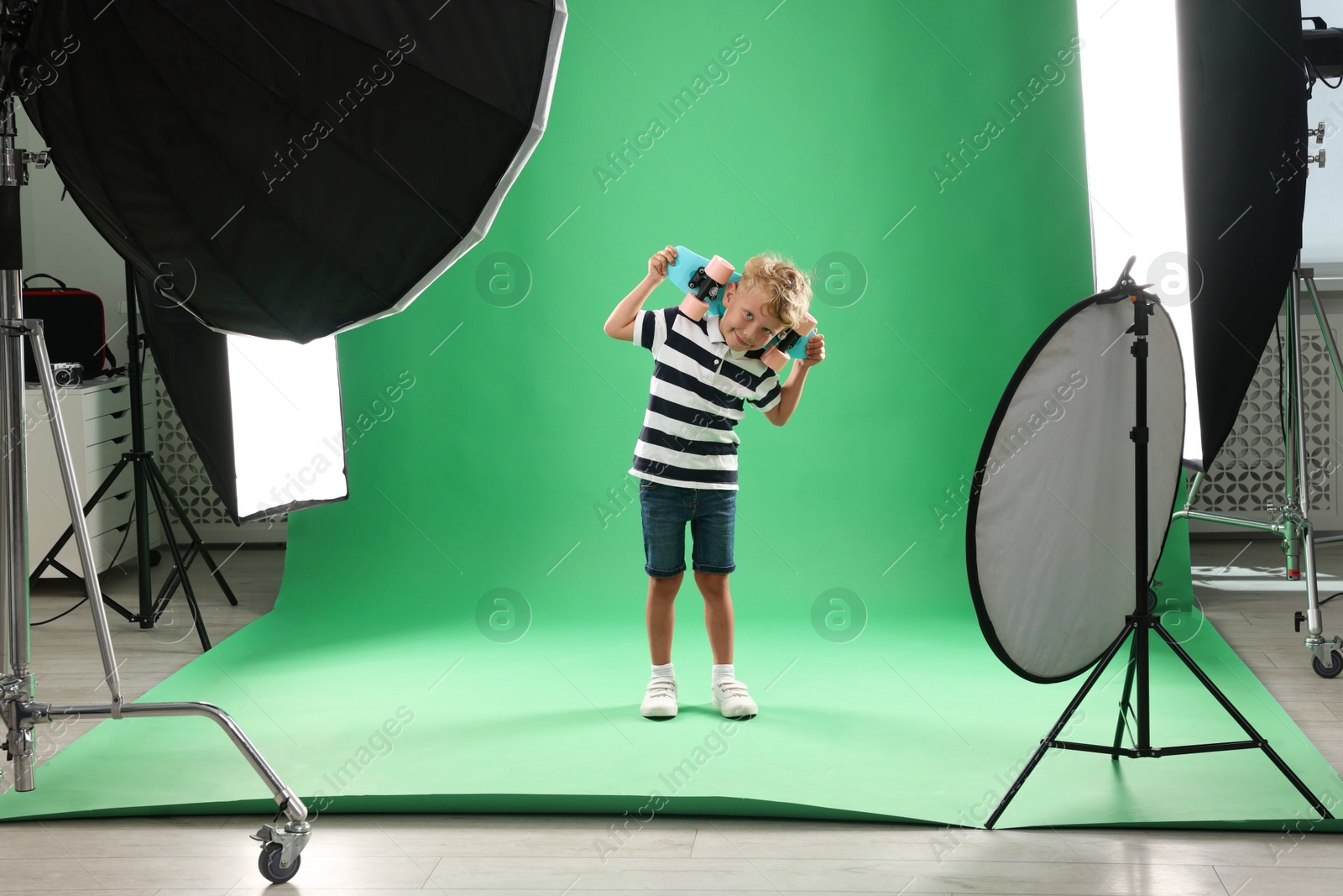 Photo of Little boy with penny board on green background in photo studio with professional equipment