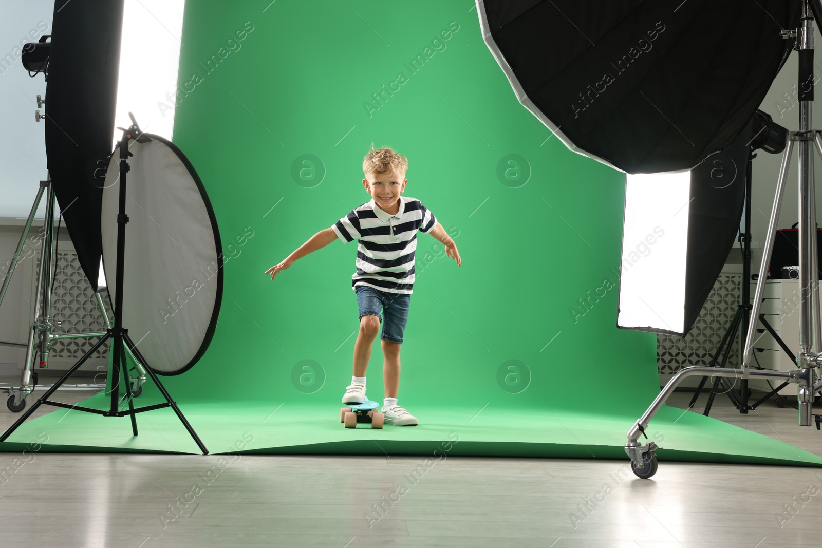 Photo of Little boy with penny board on green background in photo studio with professional equipment