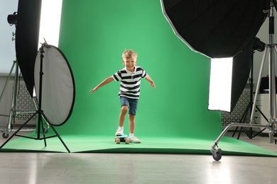 Photo of Little boy with penny board on green background in photo studio with professional equipment