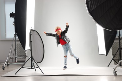Photo of Little boy on light grey background in photo studio with professional equipment