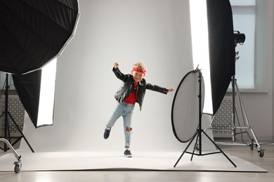 Photo of Little boy on light grey background in photo studio with professional equipment