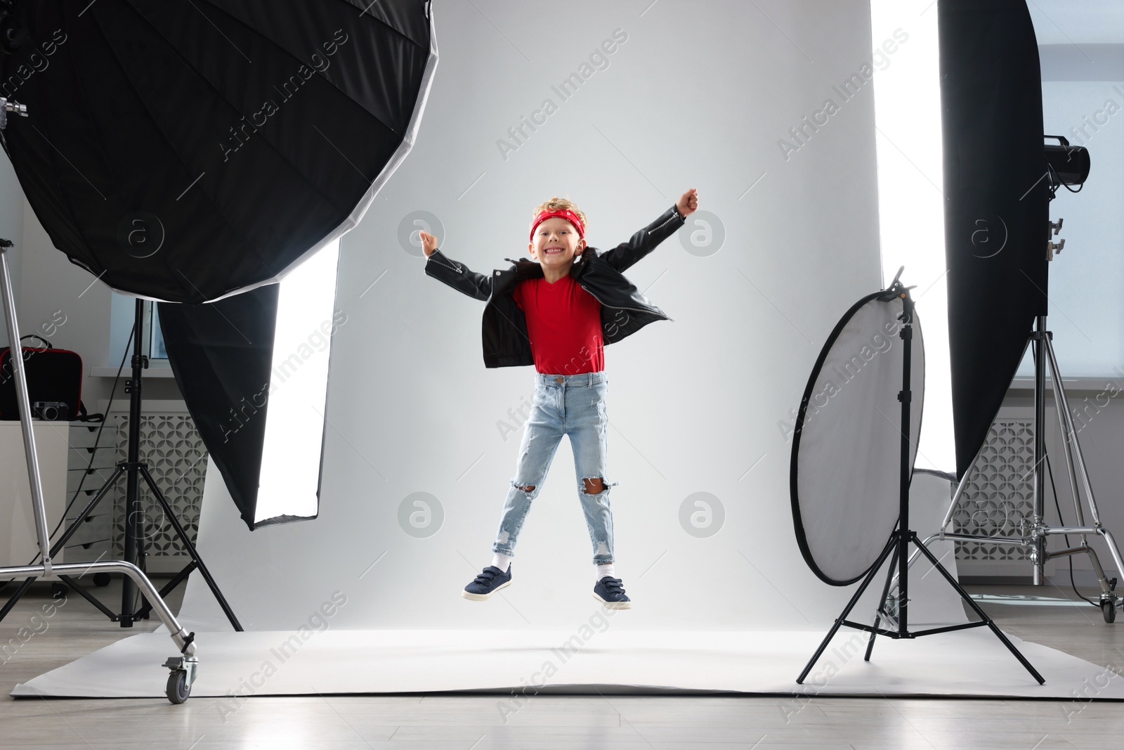 Photo of Little boy on light grey background in photo studio with professional equipment