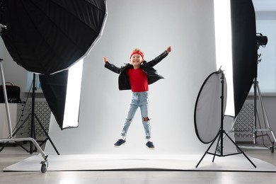 Photo of Little boy on light grey background in photo studio with professional equipment