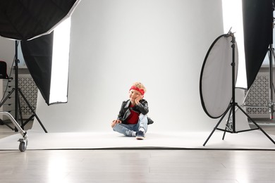 Photo of Little boy on light grey background in photo studio with professional equipment