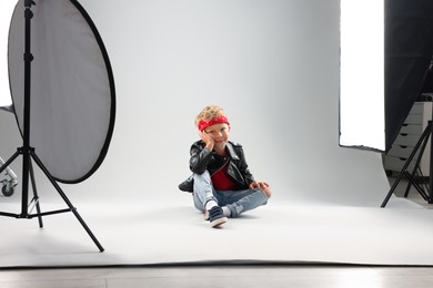 Photo of Little boy on light grey background in photo studio with professional equipment