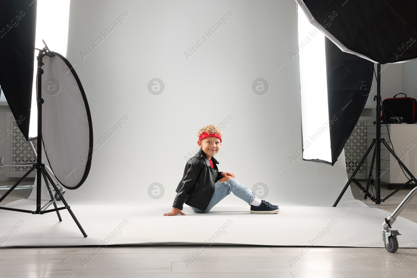 Photo of Little boy on light grey background in photo studio with professional equipment