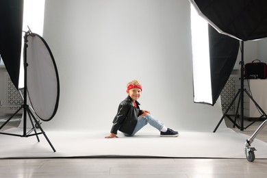 Photo of Little boy on light grey background in photo studio with professional equipment