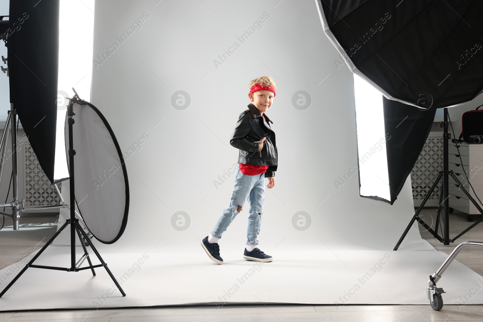 Photo of Little boy on light grey background in photo studio with professional equipment