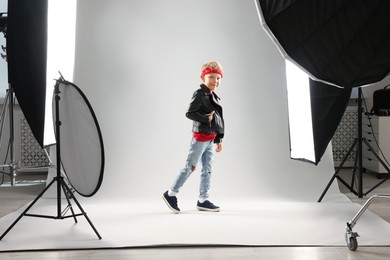 Photo of Little boy on light grey background in photo studio with professional equipment